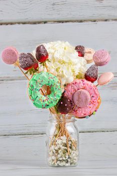 Bouquet of flowers with donuts and macarons