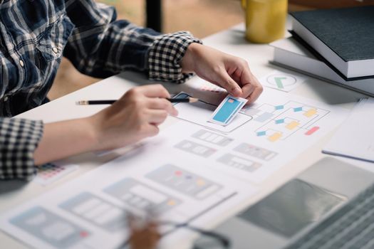 Close up App developer Ux Ui designing with paper model on mobile application prepare,