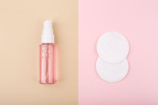 Top view of cleansing foam or gel for make up removing and cotton pads on beige and pink background. Concept of daily skin care