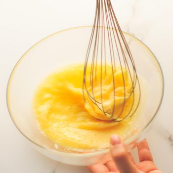 Cooking, meal and diet concept - Making of mixing eggs in bowl on marble table as homemade food flat lay, top view food brand photography flatlay and recipe for cooking blog, menu or cookbook design