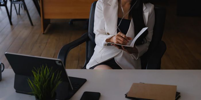 Businesswoman sitting at desk and listening music and joyful with work