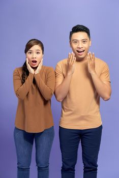 Photo of cute excited young loving couple standing isolated over purple wall background.