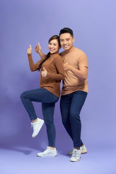 Happy young couple showing thumbs up and looking at camera