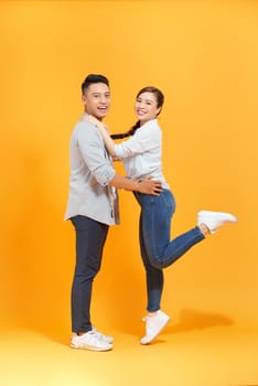 Cute couple, guy holding carrying lady lovely  moment isolated yellow color background