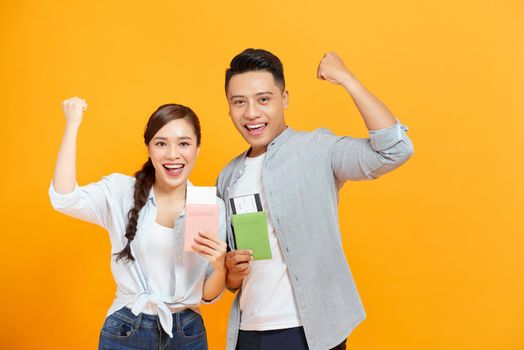 Portrait of joyful glad couple holding passport with flying tickets in hands