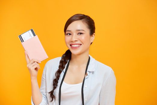 Expressive tourist woman in summer casual clothes holding passport, tickets isolated on yellow orange background.