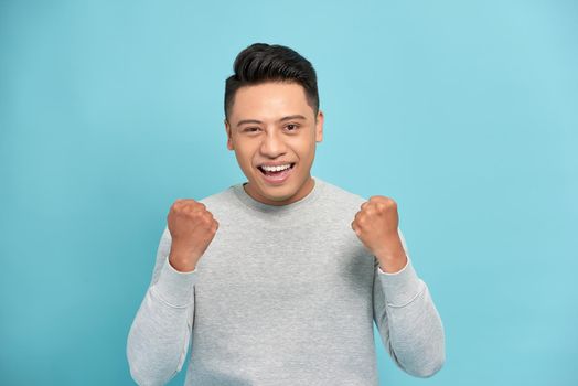 Portrait of a satisfied young man celebrating success isolated over white background