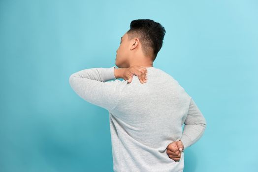 man student feel shoulder pain with blue background, asian