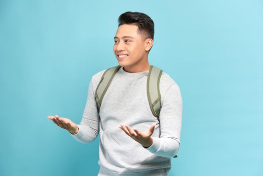 Young man with a backpack isolated on blue background with surprise facial expression
