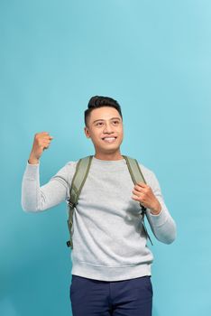 Handsome guy is celebrating a prize with raised hands over blue background