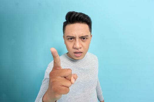 successful man angry points a finger at you, isolated on a blue background