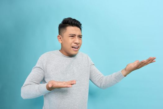 Closeup side view profile portrait of angry upset young man isolated on blue background.