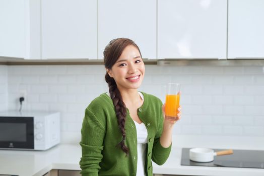 Young healthy asian woman drinking orange juice