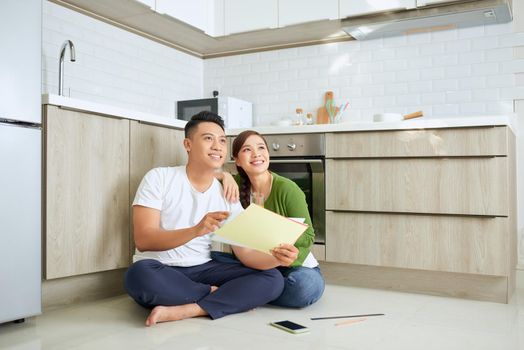 Man and woman looking at their house plans sitting in their new house