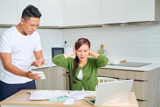 Angry young couple arguing by their many debts at home. Financial family problems concept.