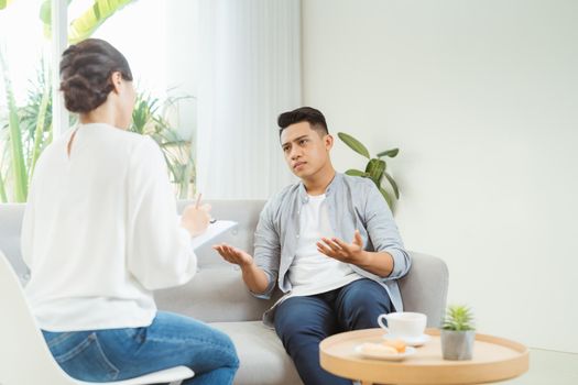 Psychologist consulting and psychological therapy session. Man in stress emotionally telling about his depression and problems to doctor. 
