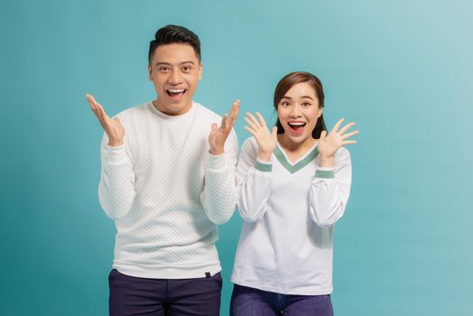 As like as two peas. A wonderful couple are posing with their palms near their chins, looking in the camera with surprised facial expressions