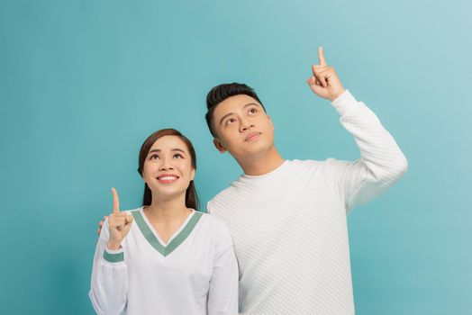 Portrait of a cheerful young couple hugging and pointing fingers up
