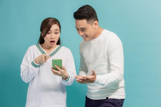 Asian young couple standing looking at the screen of a smart phone expression of surprise with an isolated background