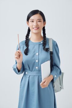 attractive female student smiling holding a bunch of notebooks in one hand and a pencil in another