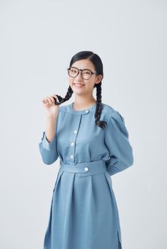 Young beautiful lady holding two hair braids in hands happily looking in camera over white background