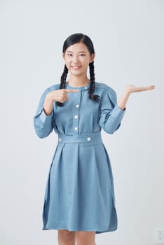 Young beautiful asian woman smiling cheerful presenting and pointing with palm of hand looking at the camera.