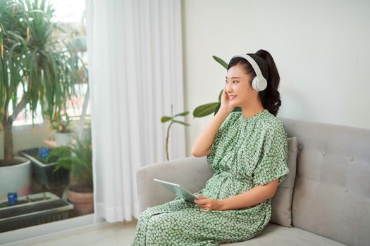 smile woman listen to music in digital tablet on sofa, asian beauty