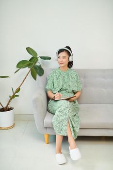 Asian women, pretty face was writing a note to that, wearing headphones to listen to music, relax the mind