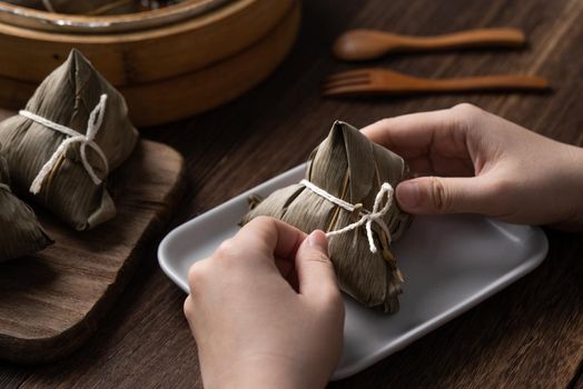 Eating Zongzi rice dumpling for Chinese traditional Dragon Boat Festival (Duanwu Festival) celebration event concept.