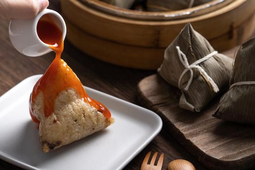 Eating Zongzi rice dumpling for Chinese traditional Dragon Boat Festival (Duanwu Festival) celebration event concept.