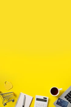 Online shopping concept. Top view of credit card purchase design concept with note, calculator and computer isolated on office yellow table background.