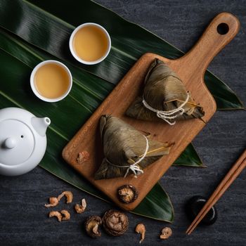 Zongzi. Rice dumpling top view design concept for Chinese traditional Dragon Boat Festival (Duanwu Festival) over dark black slate background.