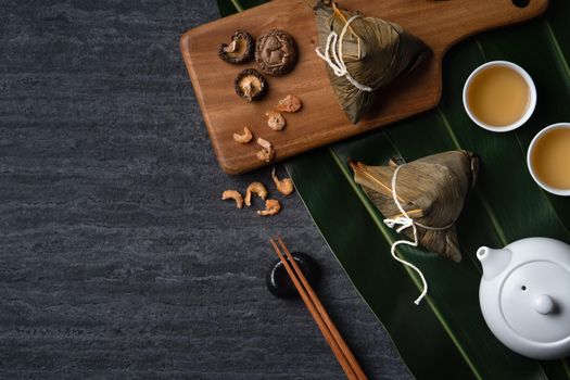 Zongzi. Rice dumpling top view design concept for Chinese traditional Dragon Boat Festival (Duanwu Festival) over dark black slate background.
