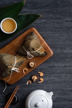 Zongzi. Rice dumpling top view design concept for Chinese traditional Dragon Boat Festival (Duanwu Festival) over dark black slate background.