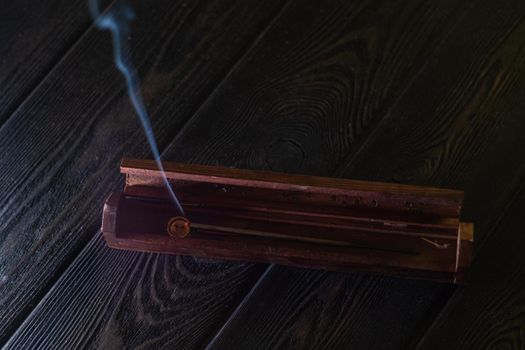 Focus on incense stick and smoke in a wooden stand. Symbol Japanese culture