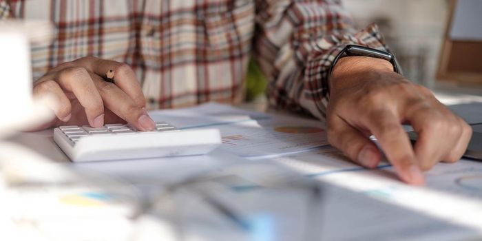 Businessman hands holding pen working on calculator and financial paperwork