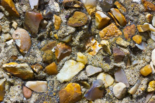 A rough pebble dash covering on an external wall showing small stones of various shapes and colours