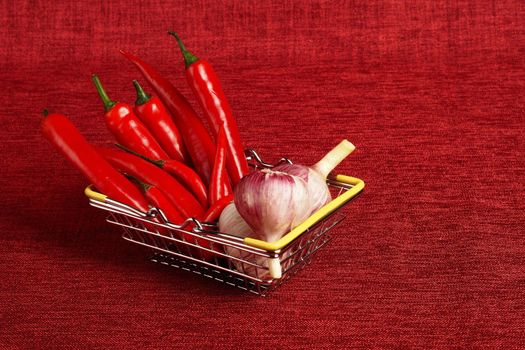 Vegetables, red peppers and fresh garlic in the shopping basket. Buying vegetables at the supermarket. red background, isolated, place for inscription. High quality photo