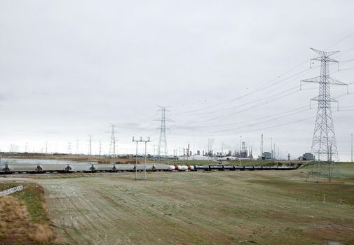 a train heading towards an oil field or refinery on a grey Alberta day 