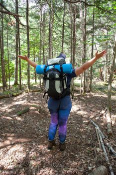 Person standing in the woods in the daytime with arms outstretched welcoming nature 