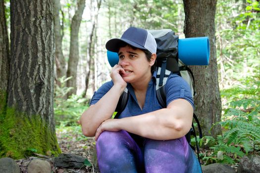 Person sitting in the forest anxiously waiting for help as they are lost 