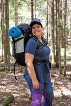 A person wearing a backpack and hat is ready to explore into the wild woods 