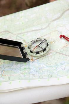 Old school navigation with paper map and digital compass outside in the woods 