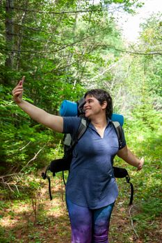 woman taking self portrait in the woods while hiking or camping 