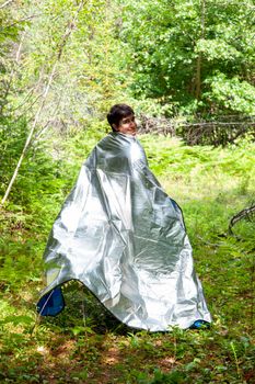 person wrapped in a tin foil blanket running through the woods 