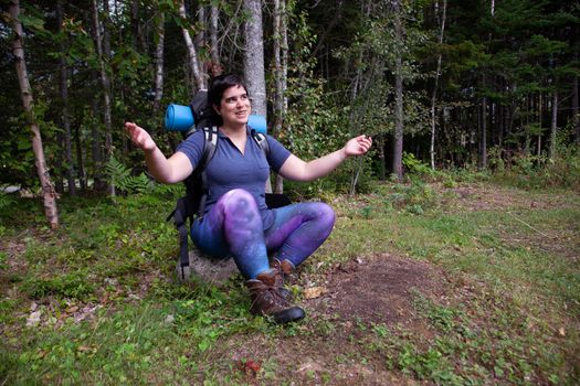 woman sitting on a rock with arms open, ready for a hike embracing the outdoors 