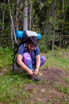 person sitting tying up the laces on their hiking boots ready for a walk 