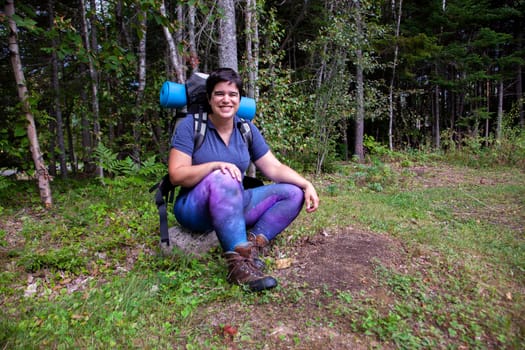  joyful woman sitting on a rock after or before a wooded hike 