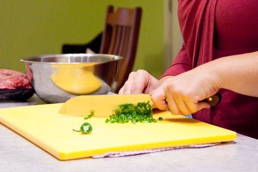 A sharp kitchen knife slicing shallots or green onions on a cutting board 