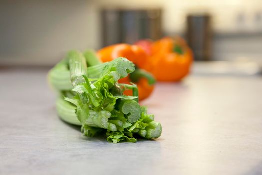 Fresh crunchy green celery stalks and round ripe tomatoes on the kitchen counter 